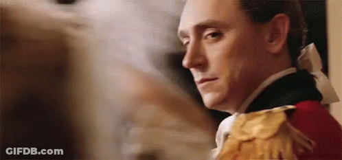 A Man In A Military Uniform Is Standing In Front Of A Painting And Looking At The Camera . GIF