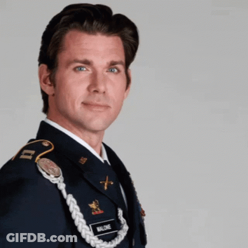 A Man In A Military Uniform Is Standing In Front Of A Sign That Says Superhero GIF