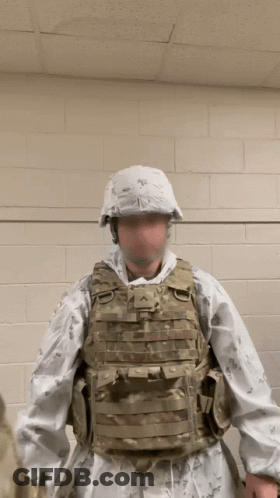 A Man In A Military Uniform Is Standing In Front Of A White Wall GIF