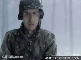 A Man In A Military Uniform Is Standing In The Snow . GIF