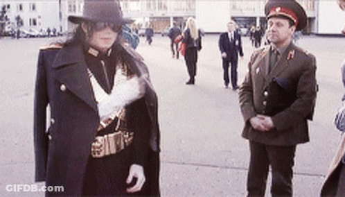 A Man In A Military Uniform Is Standing Next To Another Man GIF