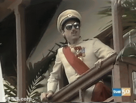 A Man In A Military Uniform Is Standing On A Balcony With A Sign That Says Tvm 50 On It GIF