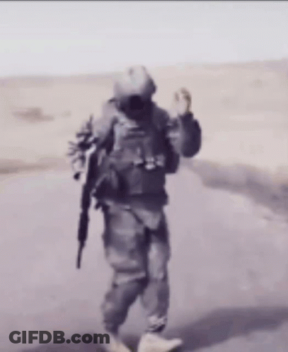 A Man In A Military Uniform Is Walking Down A Road GIF