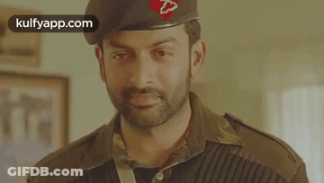 A Man In A Military Uniform Is Wearing A Beret And Looking At The Camera . GIF