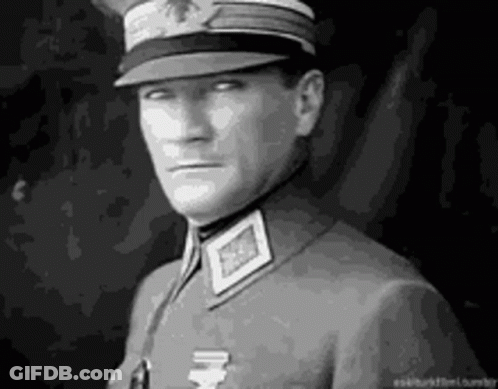 A Man In A Military Uniform Is Wearing A Hat And Looking At The Camera . GIF