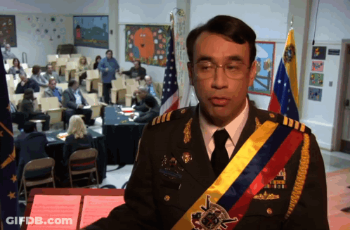 A Man In A Military Uniform Stands At A Podium In Front Of A Group Of People GIF