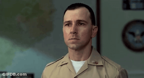 A Man In A Military Uniform Stands In Front Of A Clock GIF