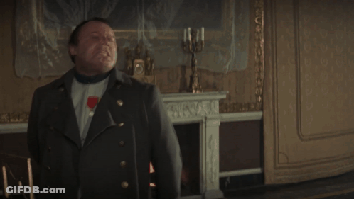A Man In A Military Uniform Stands In Front Of A Fireplace And A Clock GIF