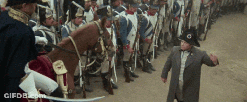 A Man In A Military Uniform Stands In Front Of A Line Of Soldiers And A Horse GIF