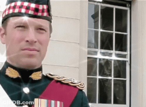 A Man In A Military Uniform Stands In Front Of A White Building GIF