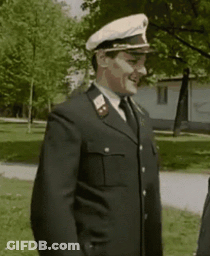 A Man In A Military Uniform With A White Hat Is Smiling . GIF