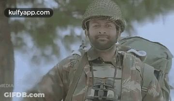 A Man In A Military Uniform With Binoculars And A Backpack Is Smiling . GIF