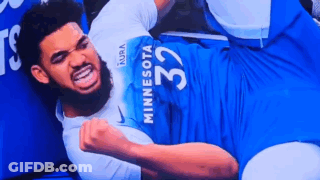 A Man In A Minnesota Jersey Is Laying On The Floor With His Fist In The Air . GIF