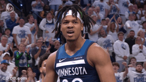 A Man In A Minnesota Jersey Stands In Front Of A Crowd Of People GIF