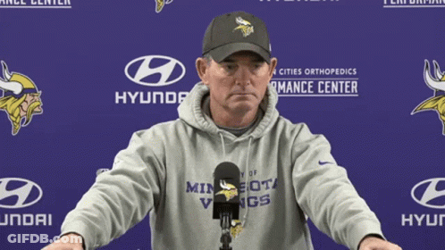 A Man In A Minnesota Vikings Hoodie Stands In Front Of A Hyundai Banner GIF