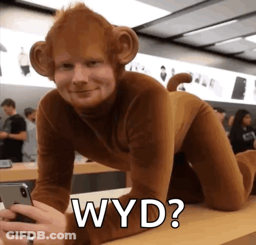 A Man In A Monkey Costume Is Sitting On A Table Holding A Phone . GIF