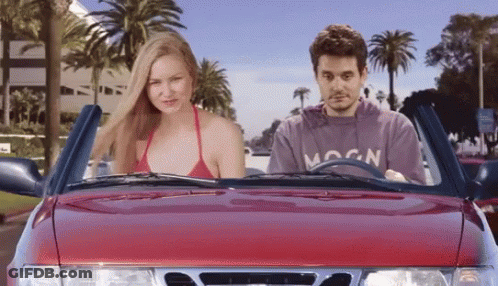A Man In A Moon Sweatshirt Is Driving A Red Car GIF