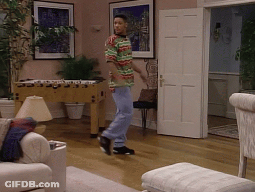 A Man In A Multicolored Shirt Is Dancing In A Living Room GIF