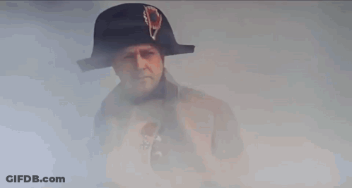 A Man In A Napoleon Hat And Coat Is Standing In Front Of A Building . GIF