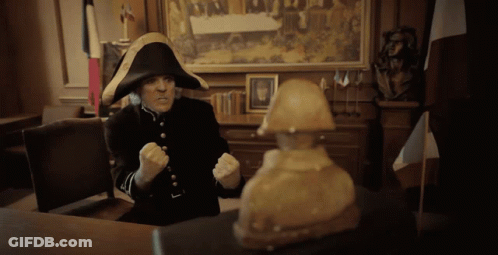 A Man In A Napoleon Hat Sitting At A Desk GIF