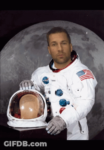 A Man In A Nasa Space Suit Holds His Helmet In Front Of A Full Moon GIF