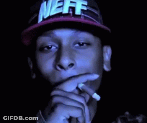 A Man In A Neff Hat Is Smoking A Cigarette . GIF
