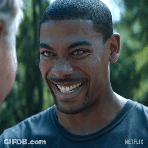 A Man In A Netflix Shirt Smiles At Another Man GIF