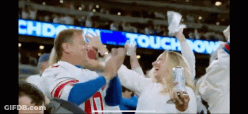 A Man In A New York Giants Jersey Is Giving A High Five To A Woman GIF