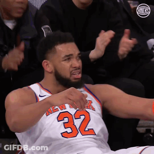 A Man In A New York Knicks Jersey Is Sitting On The Floor GIF