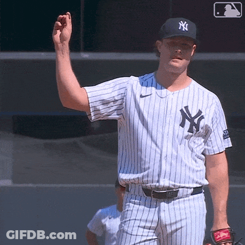 A Man In A New York Yankees Jersey Holds His Hand Up GIF