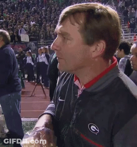 A Man In A Nike Jacket Holds A Bag Of Popcorn In Front Of A Crowd GIF