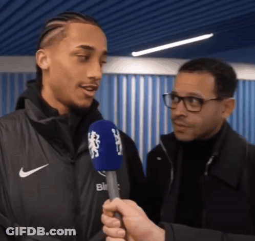 A Man In A Nike Jacket Is Being Interviewed By A Man In Glasses GIF