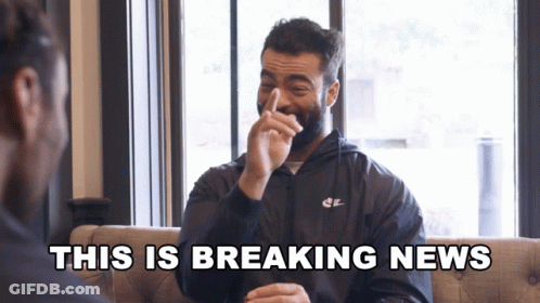 A Man In A Nike Jacket Laughs With The Words " This Is Breaking News " Behind Him GIF