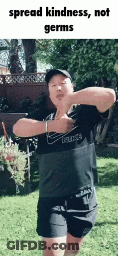 A Man In A Nike Shirt Is Dancing In A Park GIF