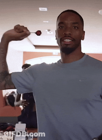 A Man In A Nike Shirt Is Holding A Dart GIF