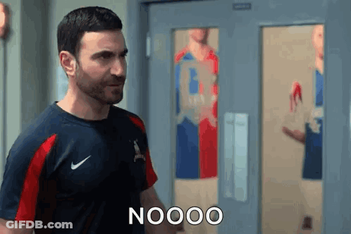 A Man In A Nike Shirt Is Standing In Front Of A Door And Talking To Someone . GIF