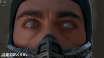 A Man In A Ninja Costume Is Standing In The Woods And Saying Come Here . GIF