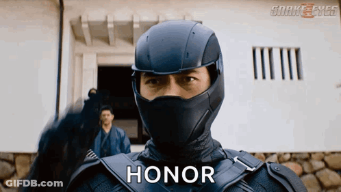 A Man In A Ninja Suit Says Honor In Front Of A Building GIF