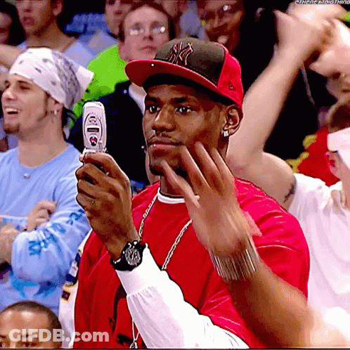 A Man In A Ny Hat Holds A Cell Phone In His Hand GIF