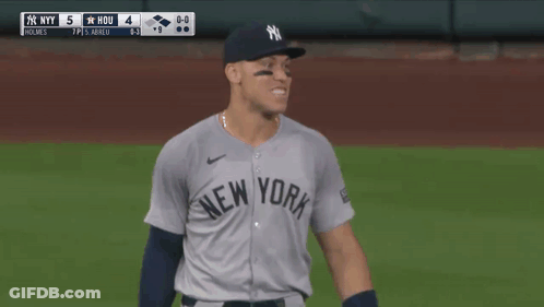 A Man In A Ny Yankees Jersey Holds His Fist Up GIF