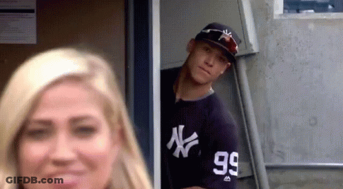 A Man In A Ny Yankees Jersey Is Peeking Out Of A Doorway . GIF