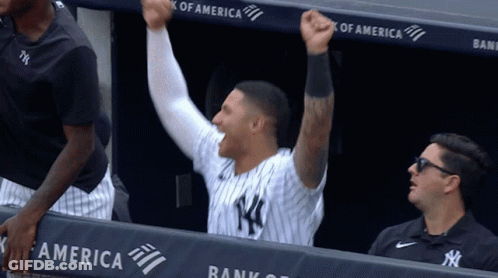 A Man In A Ny Yankees Uniform Holds His Fist Up In The Air GIF