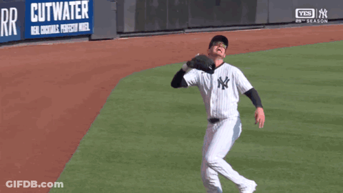 A Man In A Ny Yankees Uniform Is Catching A Baseball GIF