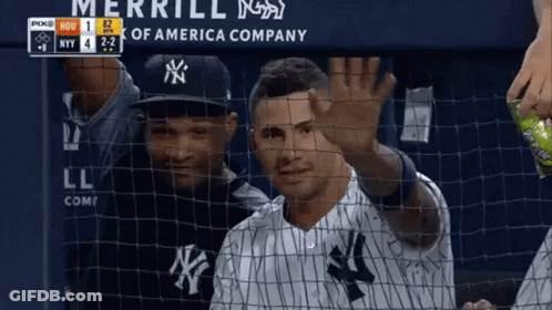 A Man In A Ny Yankees Uniform Is Waving Behind A Net GIF