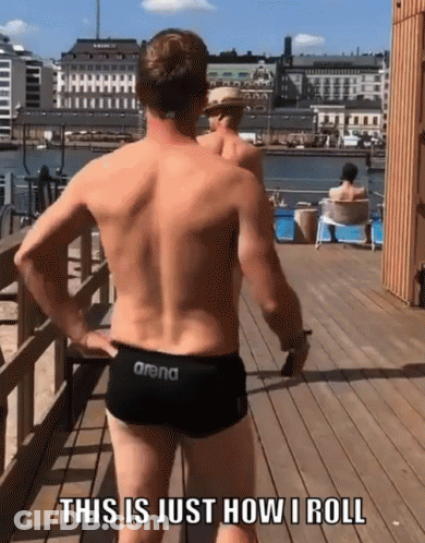 A Man In A Pair Of Arena Swim Trunks Is Standing On A Pier GIF