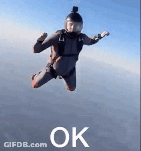A Man In A Parachute Suit Is Flying Through The Air With The Word Ok . GIF