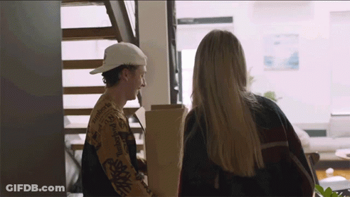A Man In A Patagonia Shirt Is Talking To A Woman In A Living Room GIF