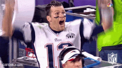 A Man In A Patriots Jersey Is Celebrating With His Arms In The Air And His Mouth Open . GIF