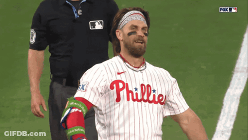A Man In A Phillies Jersey Stands On A Field GIF