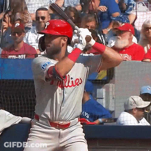 A Man In A Phillies Uniform Is Swinging At A Baseball GIF